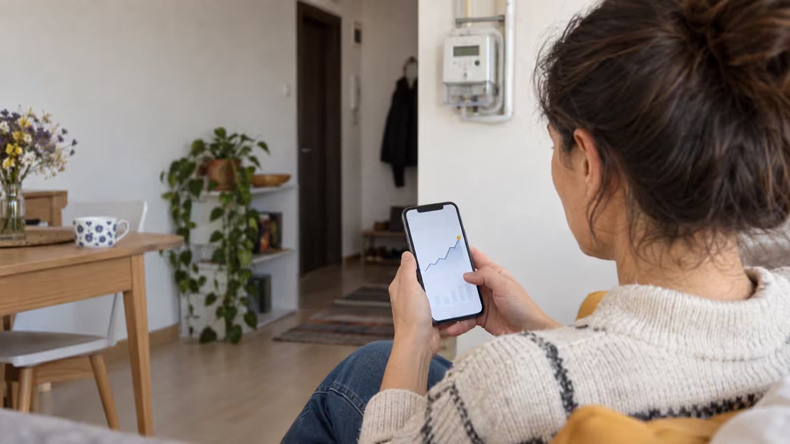 Mâini care țin un telefon cu un grafic de consum de energie